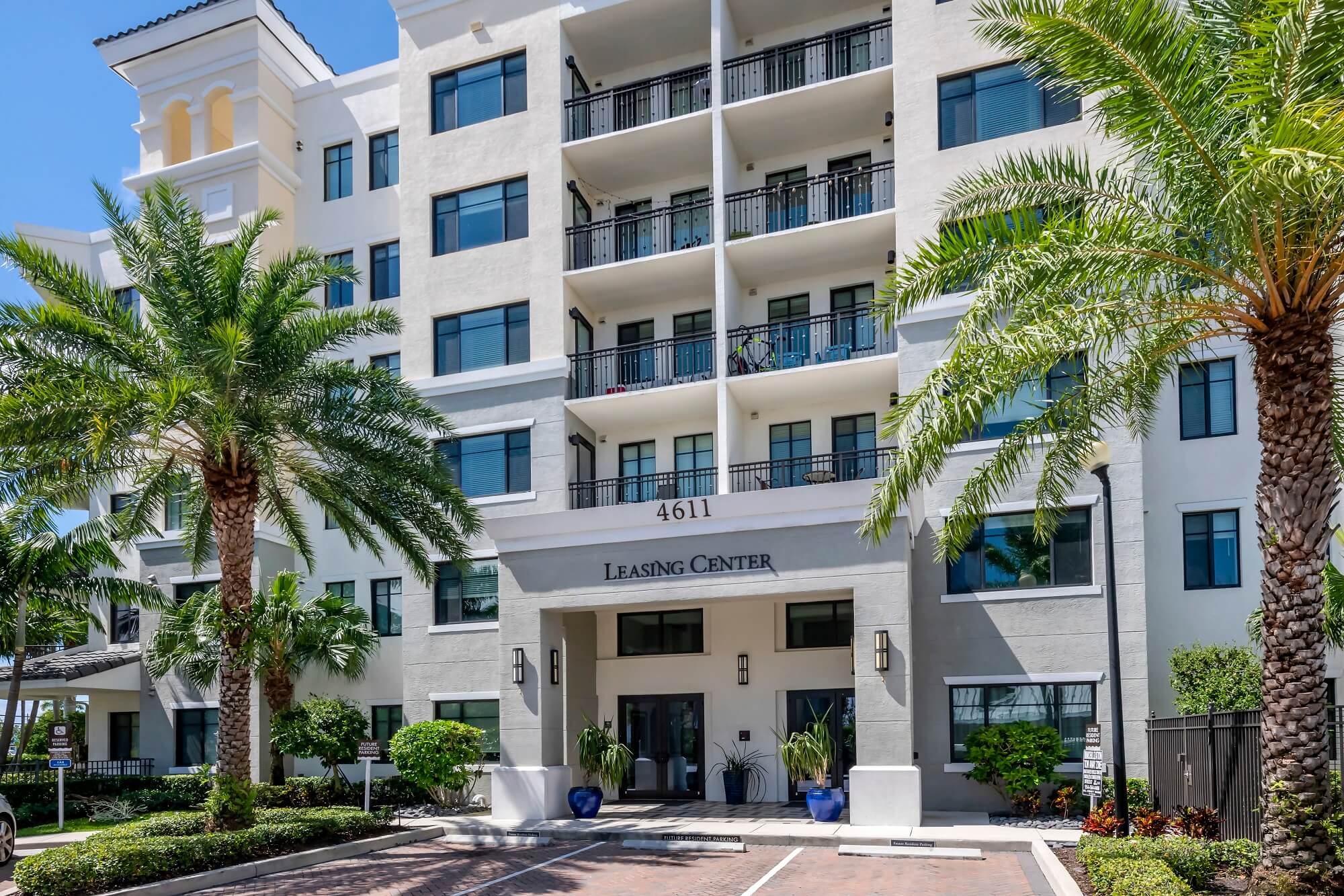 Leasing office exterior with reserved parking and palm trees