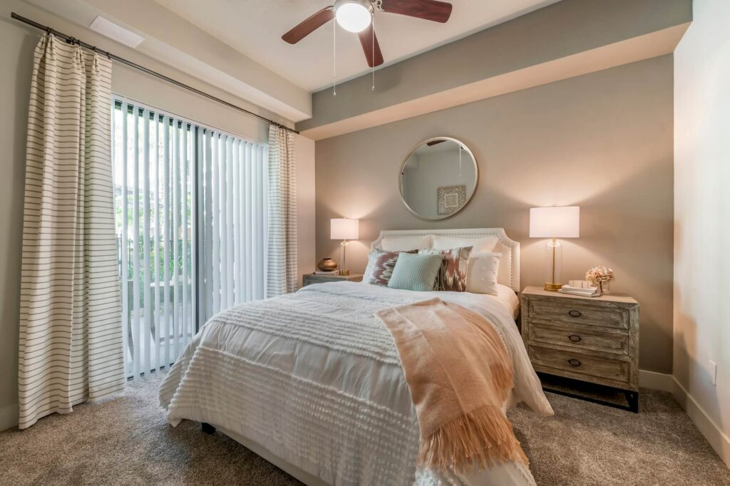 Model bedroom with glass patio doors and ceiling fan