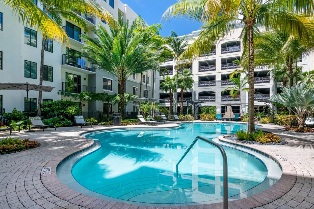 Pool courtyard with covered deck seating and palm trees