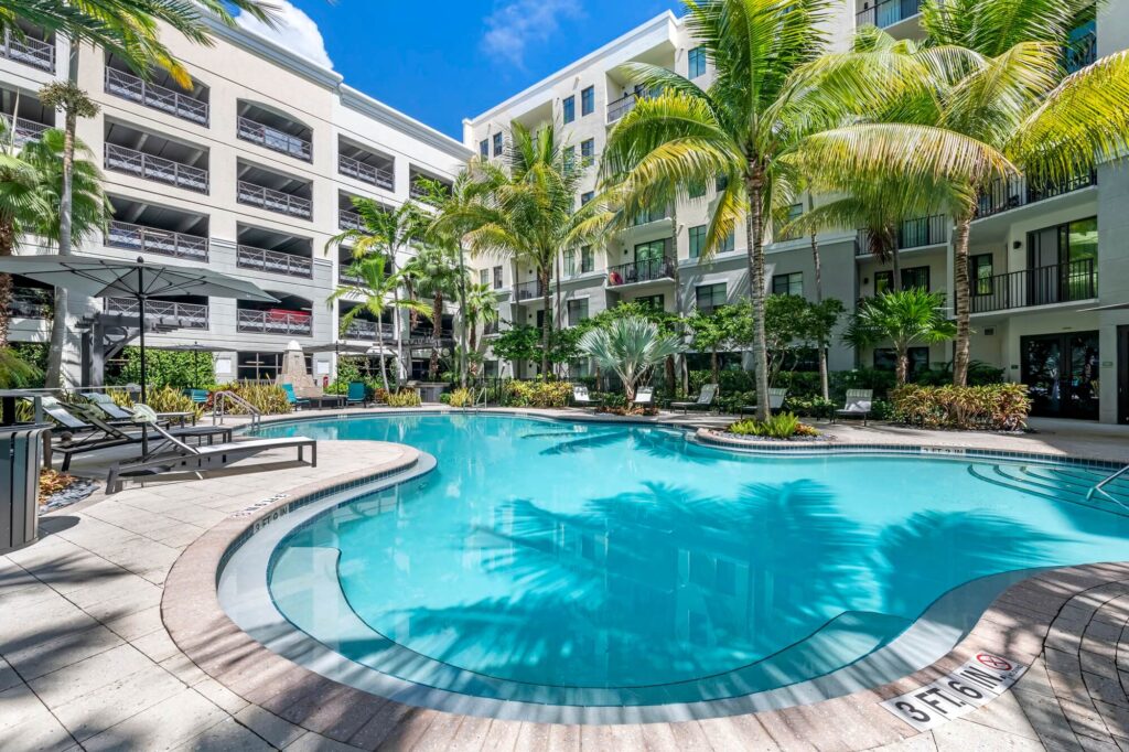 Pool courtyard with covered deck seating and palm trees