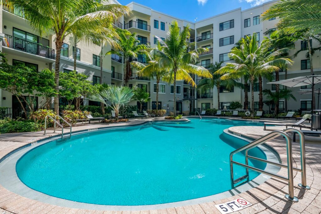 Pool courtyard with covered deck seating and palm trees